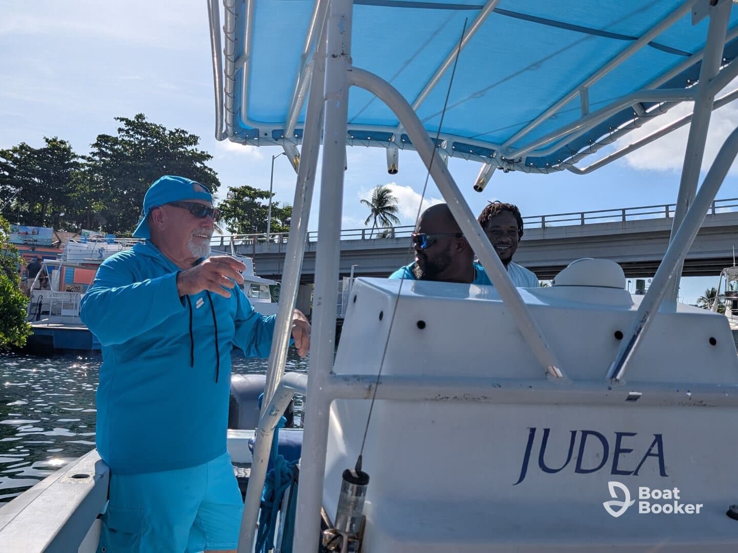 Two men enjoy a moment aboard a boat named 'Judea', showcasing a lively atmosphere on the water.