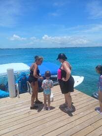 A family enjoys a sunny day by the water, interacting with a child and crew members near a boat — perfect for memorable aquatic adventures.