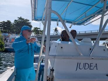Two men enjoy a moment aboard a boat named 'Judea', showcasing a lively atmosphere on the water.
