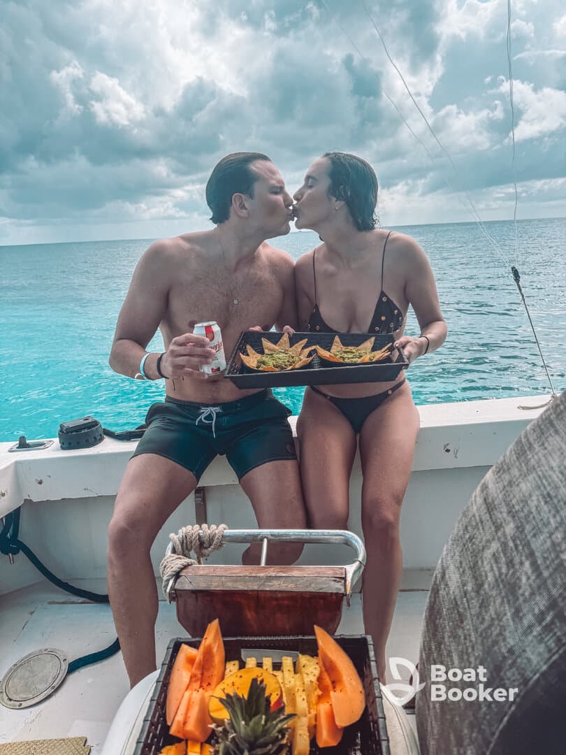 A couple shares a romantic moment on a boat, enjoying snacks and a kiss amidst stunning ocean views — perfect for a memorable getaway.