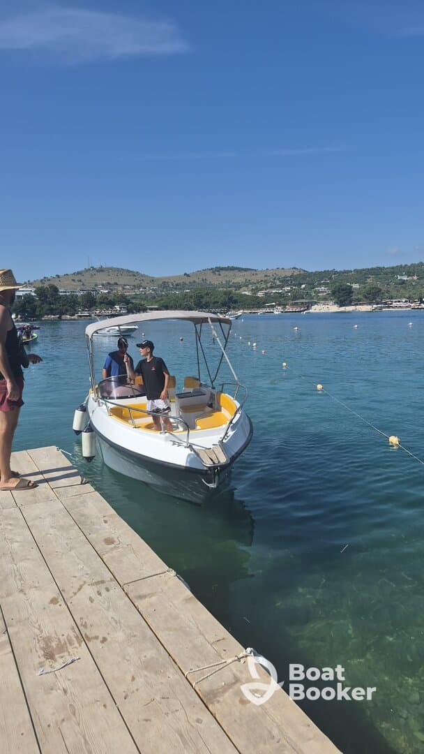 Two individuals interact on a small boat at the dock, showcasing a vibrant day on the water — perfect for boating adventures and leisure activities.