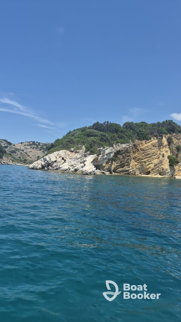 A stunning view of a rocky coastline under a clear blue sky, showcasing the natural beauty of the area — perfect for scenic boat trips and exploration.