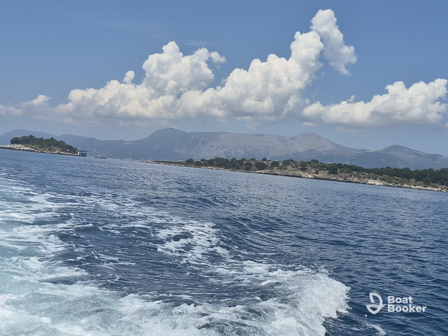 A stunning view of a coastline and distant mountains, showcasing the beauty of the open ocean — perfect for those seeking scenic boat trips.