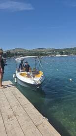 Two individuals interact on a small boat at the dock, showcasing a vibrant day on the water — perfect for boating adventures and leisure activities.