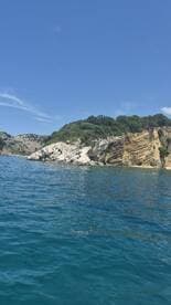 A stunning view of a rocky coastline under a clear blue sky, showcasing the natural beauty of the area — perfect for scenic boat trips and exploration.