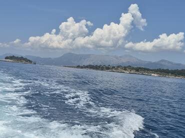 A stunning view of a coastline and distant mountains, showcasing the beauty of the open ocean — perfect for those seeking scenic boat trips.