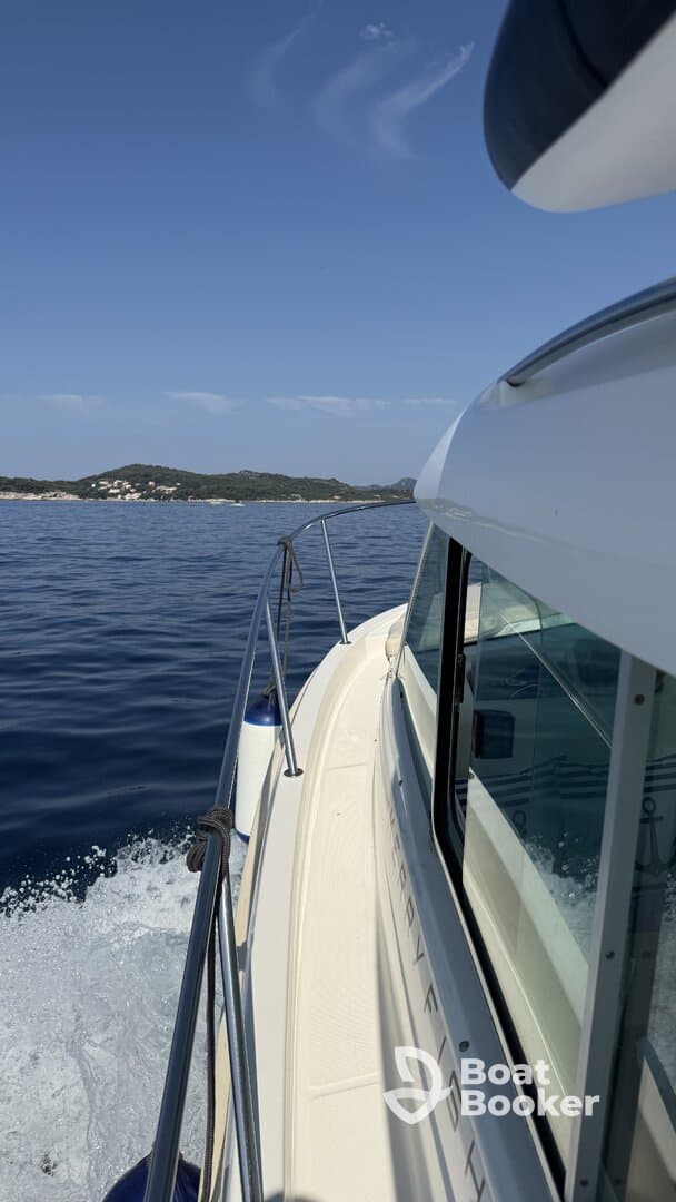 A side view of a boat cruising through calm waters, showcasing its sleek design and the beautiful landscape in the background.