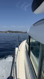 A side view of a boat cruising through calm waters, showcasing its sleek design and the beautiful landscape in the background.