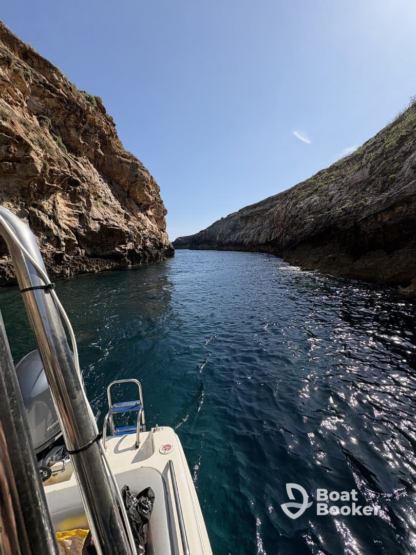 A stunning view of a boat navigating through a narrow canyon, showcasing the beautiful coastline and crystal-clear waters — perfect for exploring hidden gems.