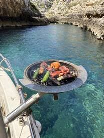 Delicious grilled sausages and zucchini sizzling on a boat's BBQ grill, perfect for a day of fun on the water.