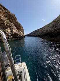 A stunning view of a boat navigating through a narrow canyon, showcasing the beautiful coastline and crystal-clear waters — perfect for exploring hidden gems.