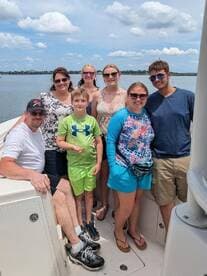A cheerful group of family and friends poses together on a boat, enjoying a sunny day on the water — perfect for creating lasting memories.