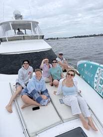 A cheerful group of friends relaxes on the deck of a boat, enjoying their time together on the water — perfect for memorable outings and celebrations.