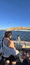 A lively scene aboard a pontoon boat as a child splashes in the water while adults enjoy drinks — perfect for summer fun and family outings on the lake.