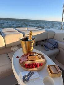 A beautifully arranged charcuterie board with fresh raspberries and a bottle of champagne on a boat, perfect for a relaxing day on the water.
