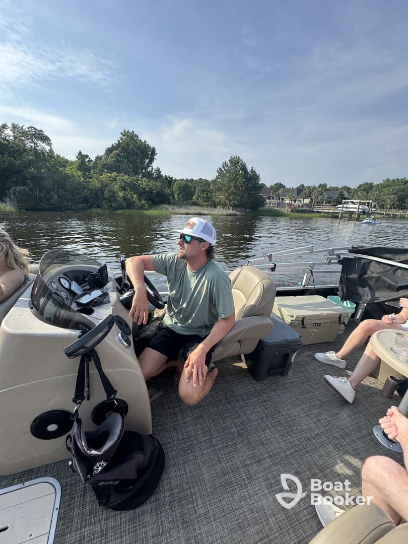 A relaxed scene inside a pontoon boat, featuring a man at the helm and guests enjoying the comfortable seating — perfect for a day on the water.