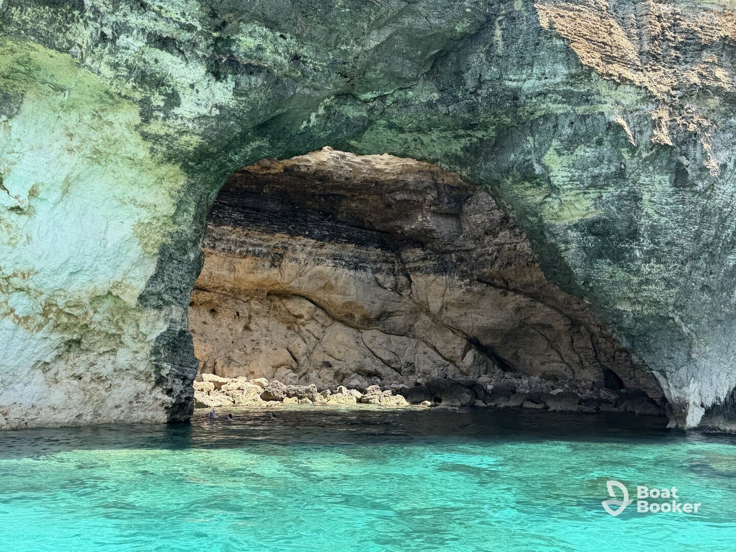 A stunning view of a coastal cave with crystal-clear waters, perfect for exploring and enjoying the natural beauty of the area.
