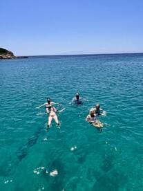 A group of friends enjoys a refreshing swim in crystal-clear waters, perfect for a fun day out on the boat.