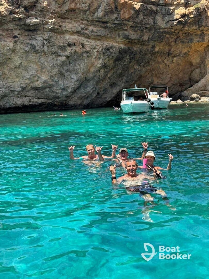 A lively group enjoys swimming in crystal-clear waters, showcasing a fun day of snorkeling and relaxation in a stunning natural setting.