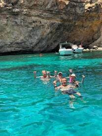A lively group enjoys swimming in crystal-clear waters, showcasing a fun day of snorkeling and relaxation in a stunning natural setting.
