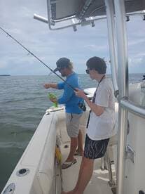 Two individuals enjoy a fishing trip on a boat, showcasing the excitement of on-water activities and bonding moments.