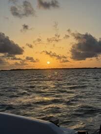 A serene sunset view over the water, captured from the deck of a boat, showcasing the tranquil beauty of evening cruises.