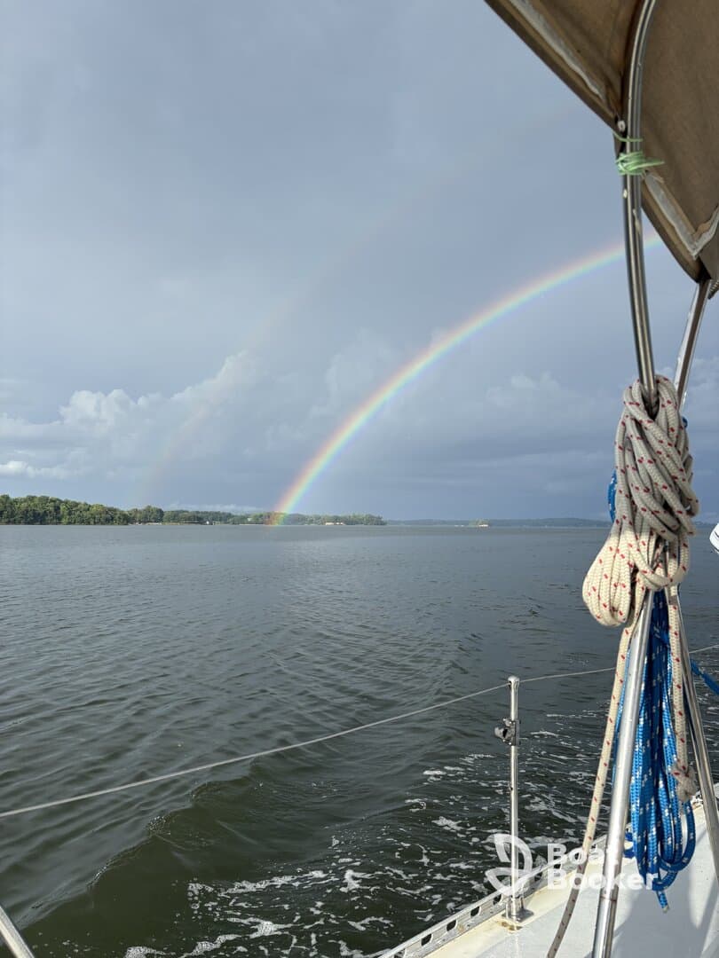 A stunning view of a rainbow arching over calm waters, captured from a sailboat — a perfect moment for nature lovers and sailing enthusiasts.