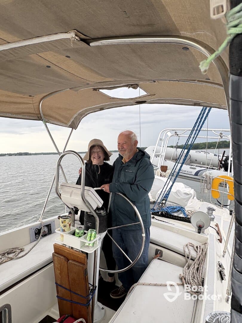 A couple enjoys their time at the helm of a sailboat, showcasing the cozy interior space perfect for navigating the waters together.