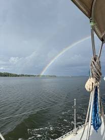 A stunning view of a rainbow arching over calm waters, captured from a sailboat — a perfect moment for nature lovers and sailing enthusiasts.
