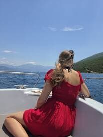 A woman enjoys a serene moment on a boat, surrounded by stunning scenery and clear blue waters — perfect for relaxation and exploration.