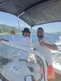 Two friends enjoy a sunny day on the water, showcasing smiles and positive vibes while navigating their boat — a perfect moment for adventure seekers.