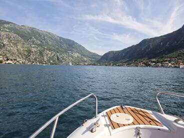 A stunning view from the bow of a boat, showcasing the picturesque mountains and coastal town along the water's edge — perfect for exploring scenic destinations.