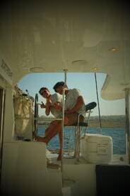 Two friends enjoy a fun moment aboard a boat, showcasing the joy of being on the water together — perfect for group outings and celebrations.