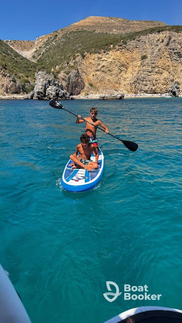 Two boys enjoy paddleboarding in crystal-clear waters, showcasing a fun summer activity amidst stunning natural scenery.