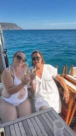 Two friends celebrate with cocktails on a boat, enjoying the beautiful ocean view — perfect for memorable moments on the water.