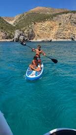 Two boys enjoy paddleboarding in crystal-clear waters, showcasing a fun summer activity amidst stunning natural scenery.