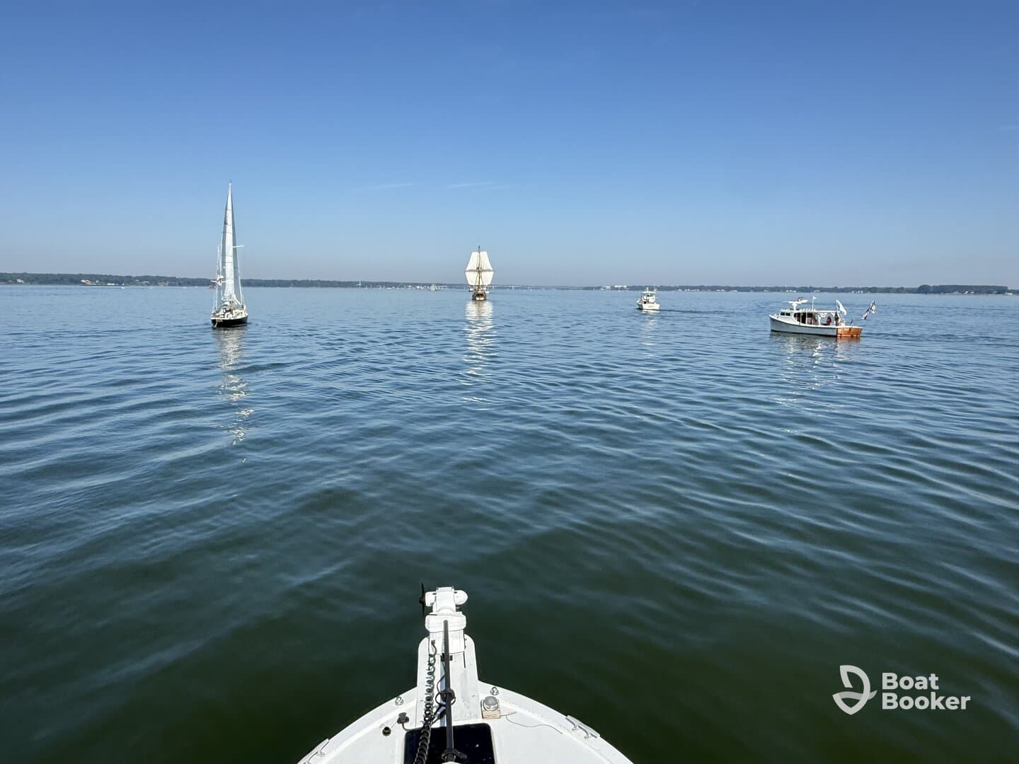 A serene view of multiple boats sailing on calm waters under a clear blue sky, showcasing the beauty of a day on the water.