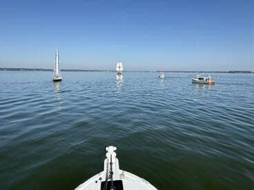 A serene view of multiple boats sailing on calm waters under a clear blue sky, showcasing the beauty of a day on the water.