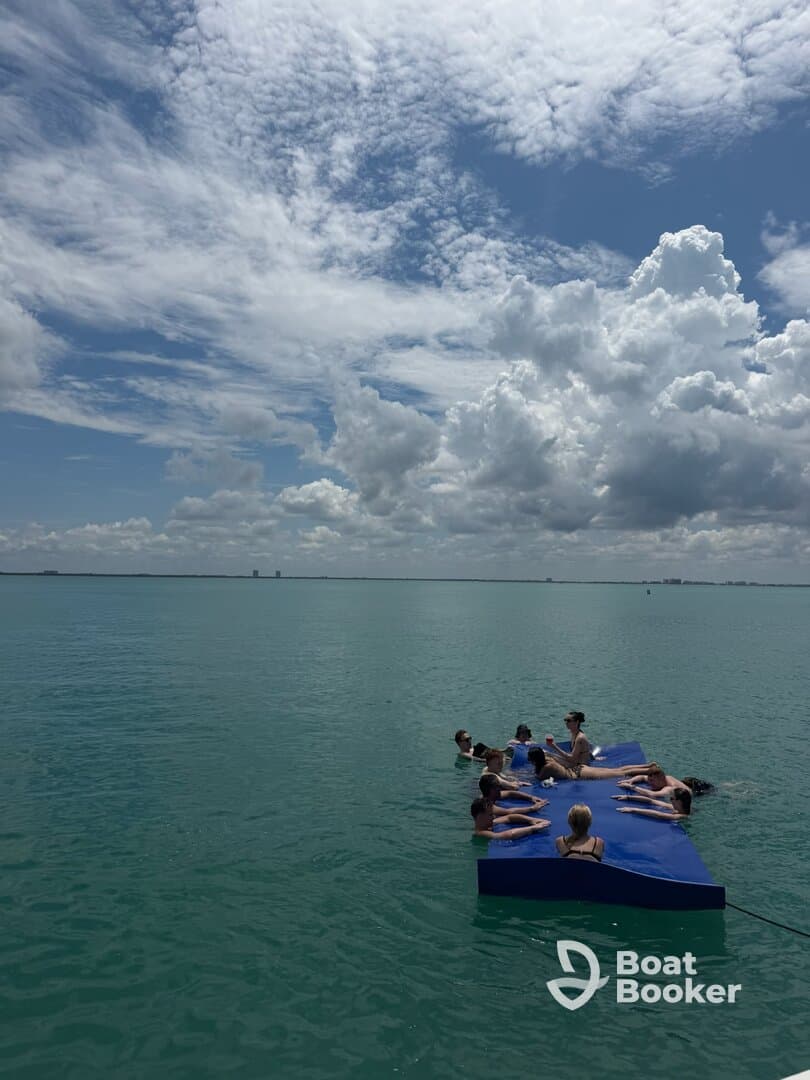 A lively group enjoys a day on a floating mat in clear turquoise waters, perfect for relaxation and fun under the sun.
