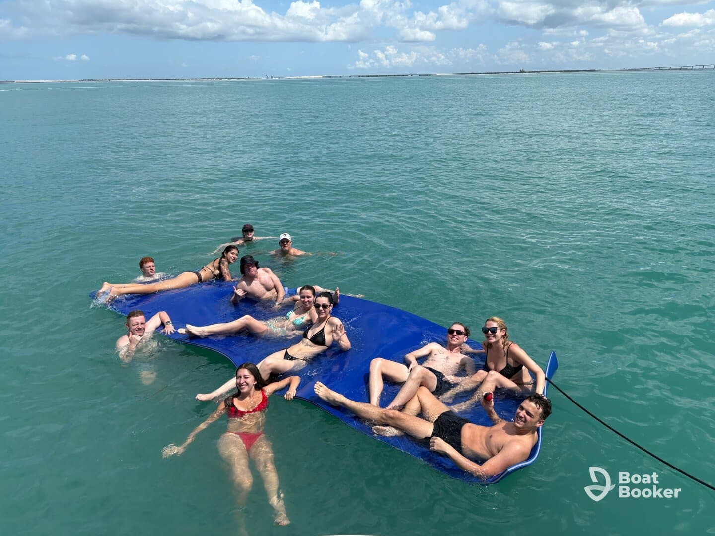A lively group enjoys a sunny day on a floating mat in clear waters, perfect for fun and relaxation during their boating adventure.