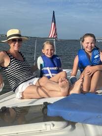 A joyful family enjoys a sunny day on the boat, showcasing the fun of summer adventures on the water with life jackets for safety.