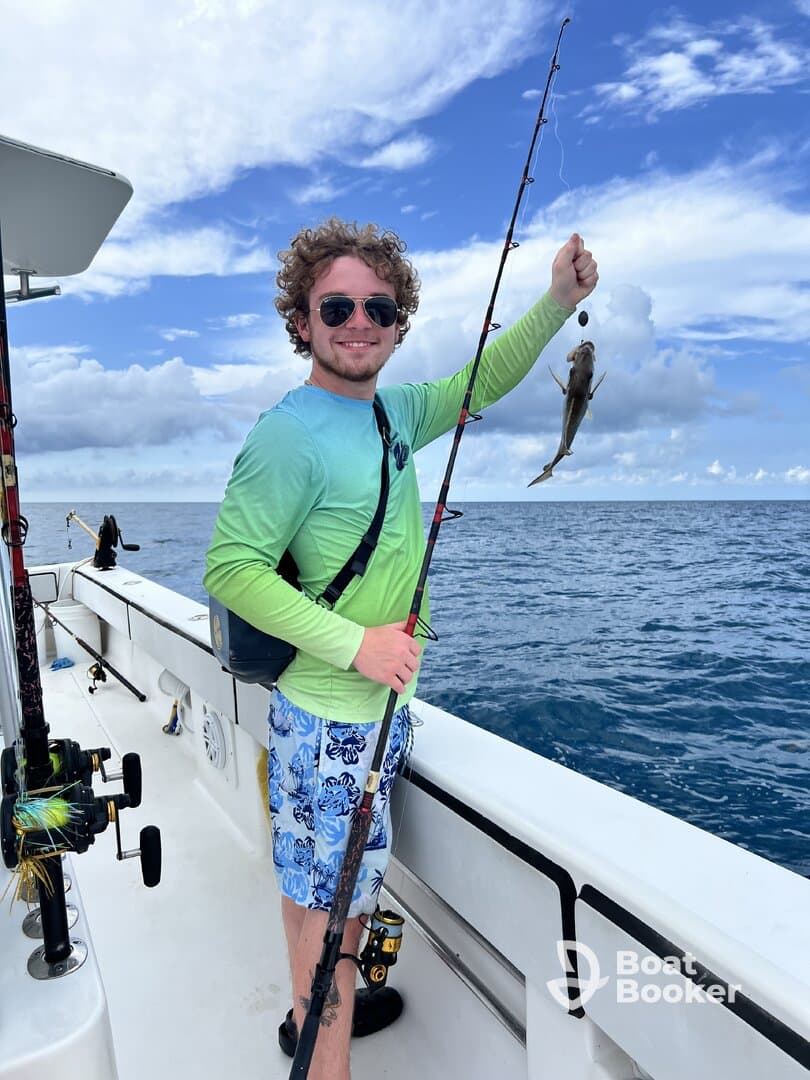 A young angler proudly displays his catch while fishing on a boat, showcasing the excitement of a day on the water.