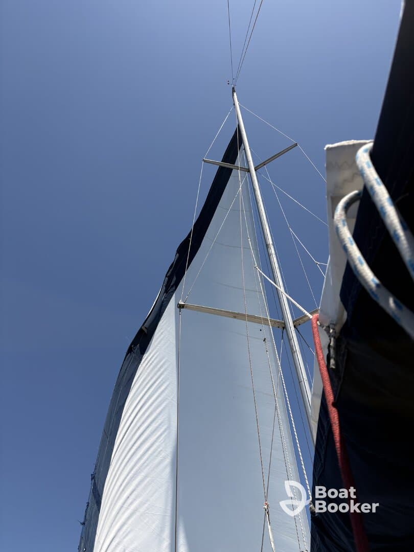 A close-up view of a sailboat's sail against a clear blue sky, showcasing the vessel's structure and design while underway.