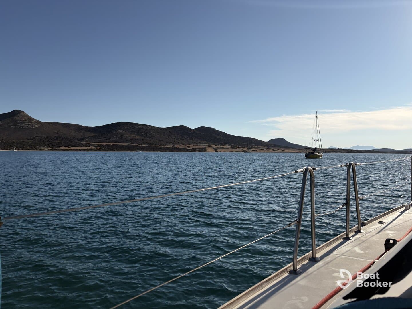 A serene view of a sailboat on calm waters, framed by rolling hills and a clear sky, perfect for showcasing the beauty of sailing adventures.