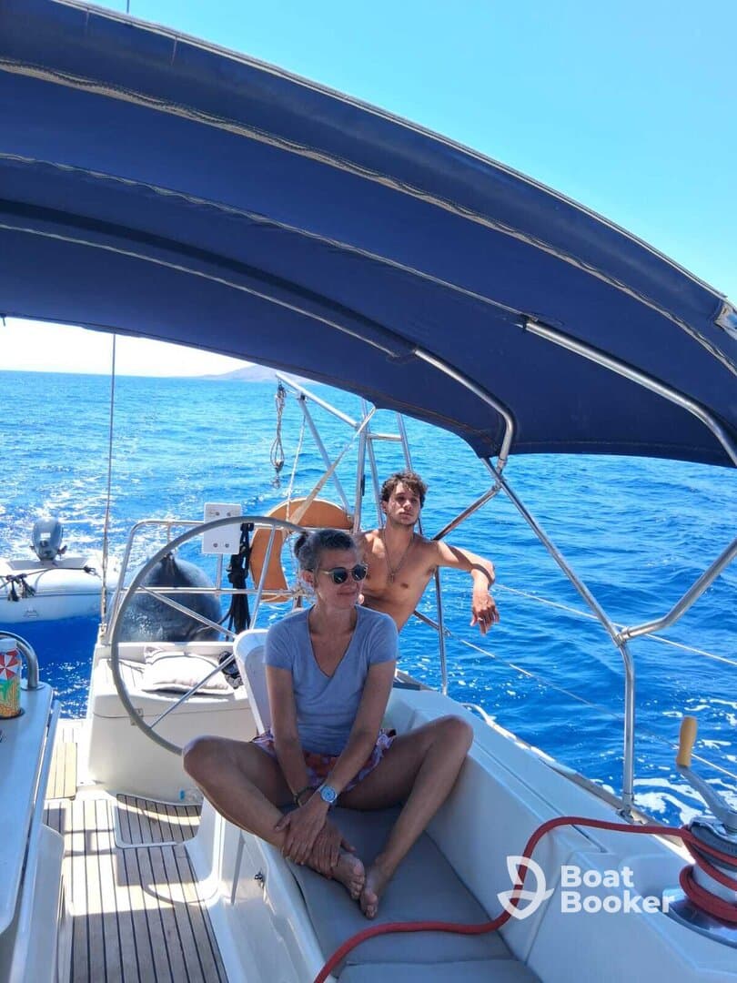 Two guests relax in the cabin of a sailboat, enjoying the serene blue waters — a perfect setting for a leisurely day at sea.