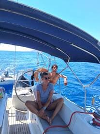 Two guests relax in the cabin of a sailboat, enjoying the serene blue waters — a perfect setting for a leisurely day at sea.