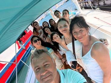 A joyful group of friends poses for a selfie aboard a boat, capturing the essence of their fun-filled day on the water.