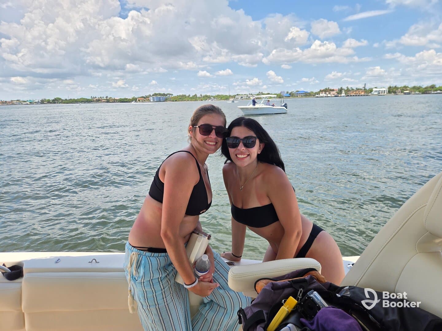 Two friends enjoy a sunny day on the water, smiling and posing on the boat — a perfect moment for summer adventures and boating fun.