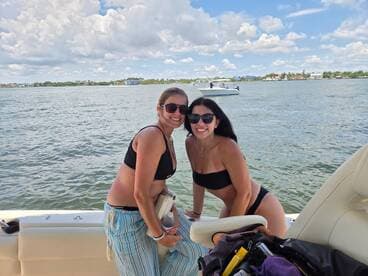 Two friends enjoy a sunny day on the water, smiling and posing on the boat — a perfect moment for summer adventures and boating fun.