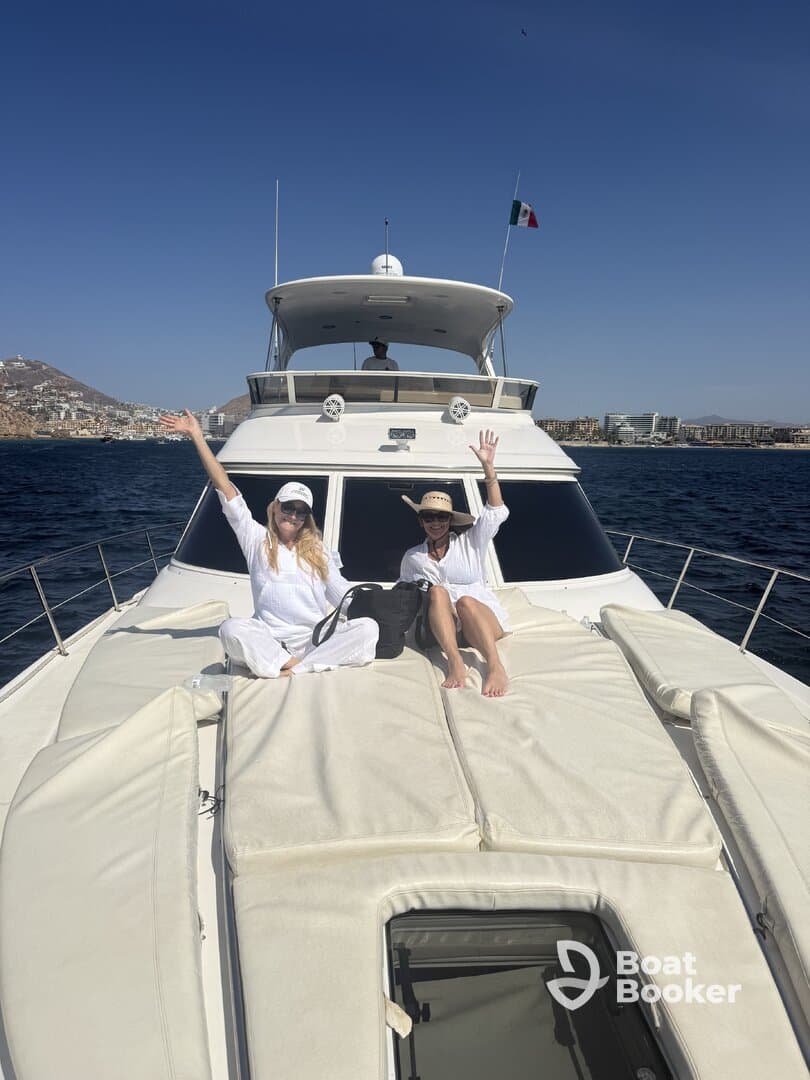 Two friends enjoy a sunny day on a yacht, waving and celebrating their time on the water — perfect for memorable outings and adventures.